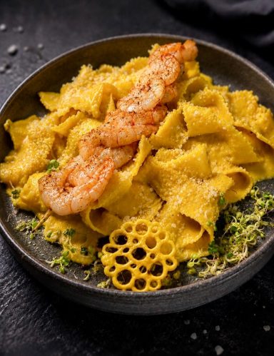 Pasta mit Garnelen, Zitronenabrieb und einer dekorativen Beilage aus Teig.