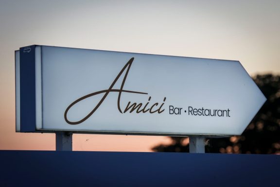 Schilder mit der Aufschrift „Amici“ und dem Hinweis auf ein Restaurant.