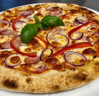 Pizza mit Käse, Paprika, Zwiebeln und frischem Basilikum auf einem dünnen Teigboden.